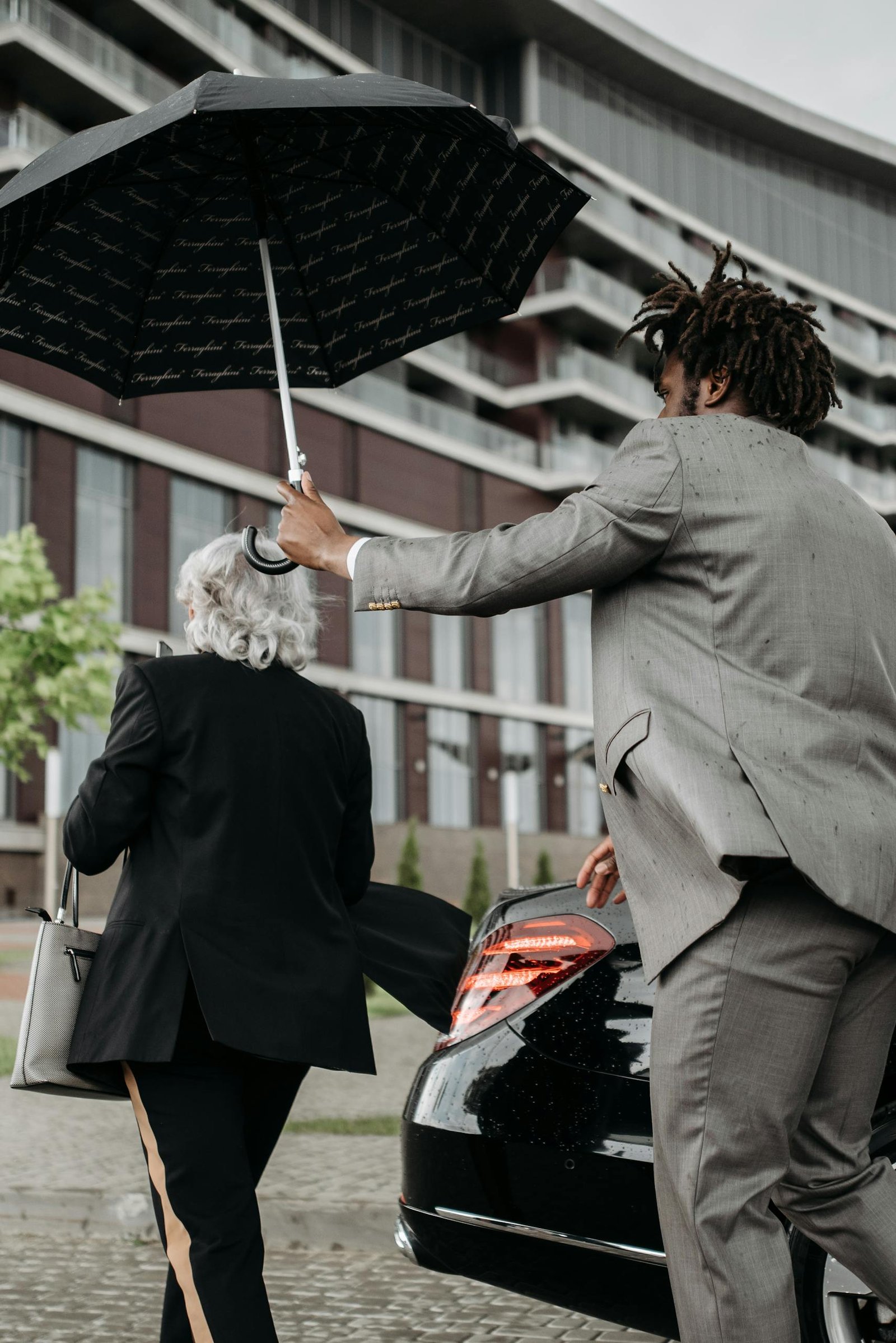 Private concierge assisting a client with an umbrella